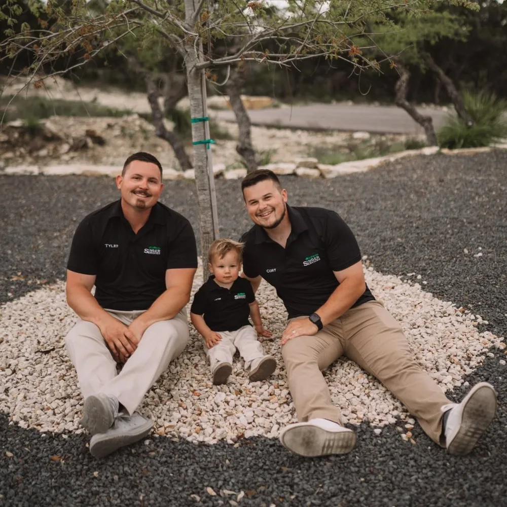 Tyler and Cory Singer in Singer Services shirts, sitting on a finished gravel bed on one of their jobs