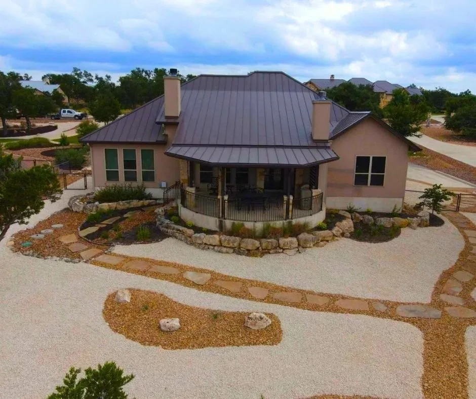 Aerial view of a xeriscaped front yard with decorative gravel, flagstone paths, and a limestone boulder retaining wall
