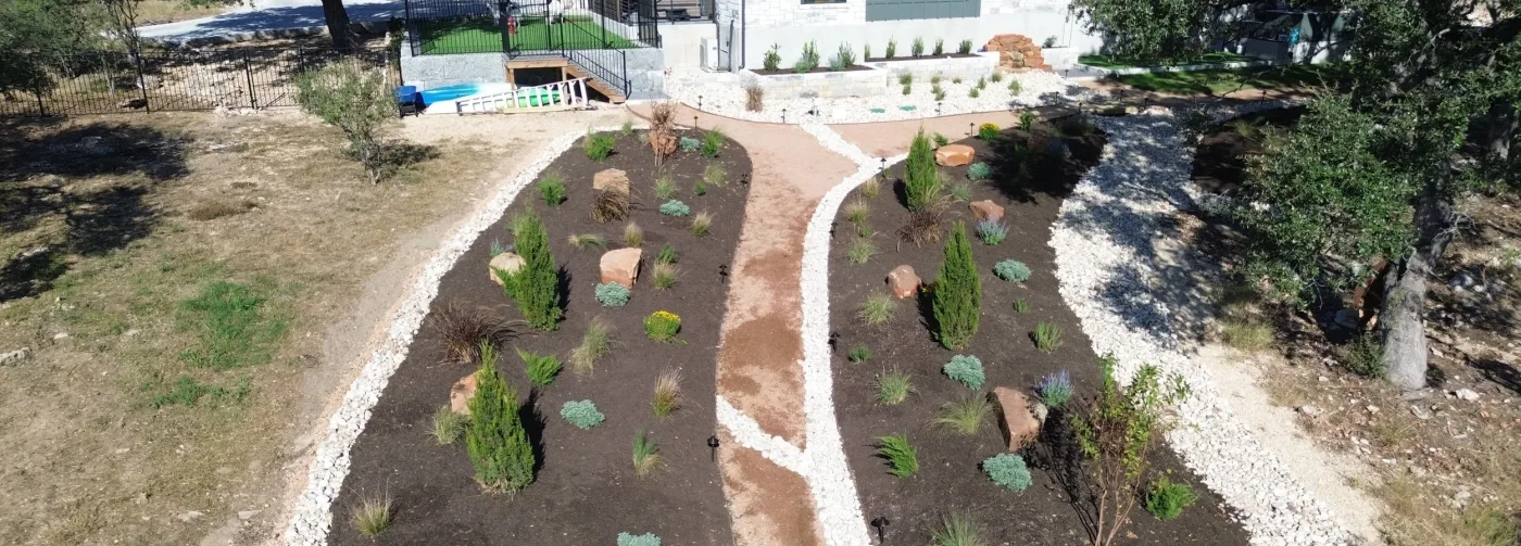 Aerial view of newly planted native beds with junipers, agaves, and ornamental grasses divided by a decomposed granite path