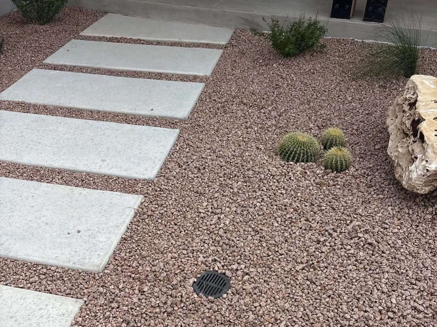Concrete steppers set through gravel with barrel cactus and a limestone boulder at a Boerne home