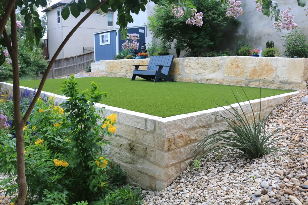 Turf lawn behind a cut limestone retaining wall on a Bulverde property