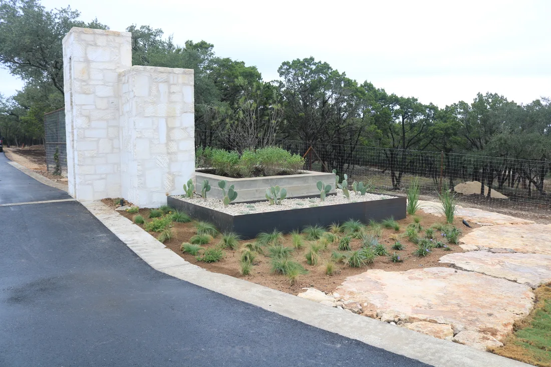 Limestone entry monument at Ranches at Canyon Crossing with raised planters of native grasses