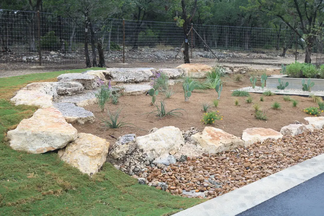 Xeriscaped entry bed with limestone boulders, agave, and native grasses over gravel