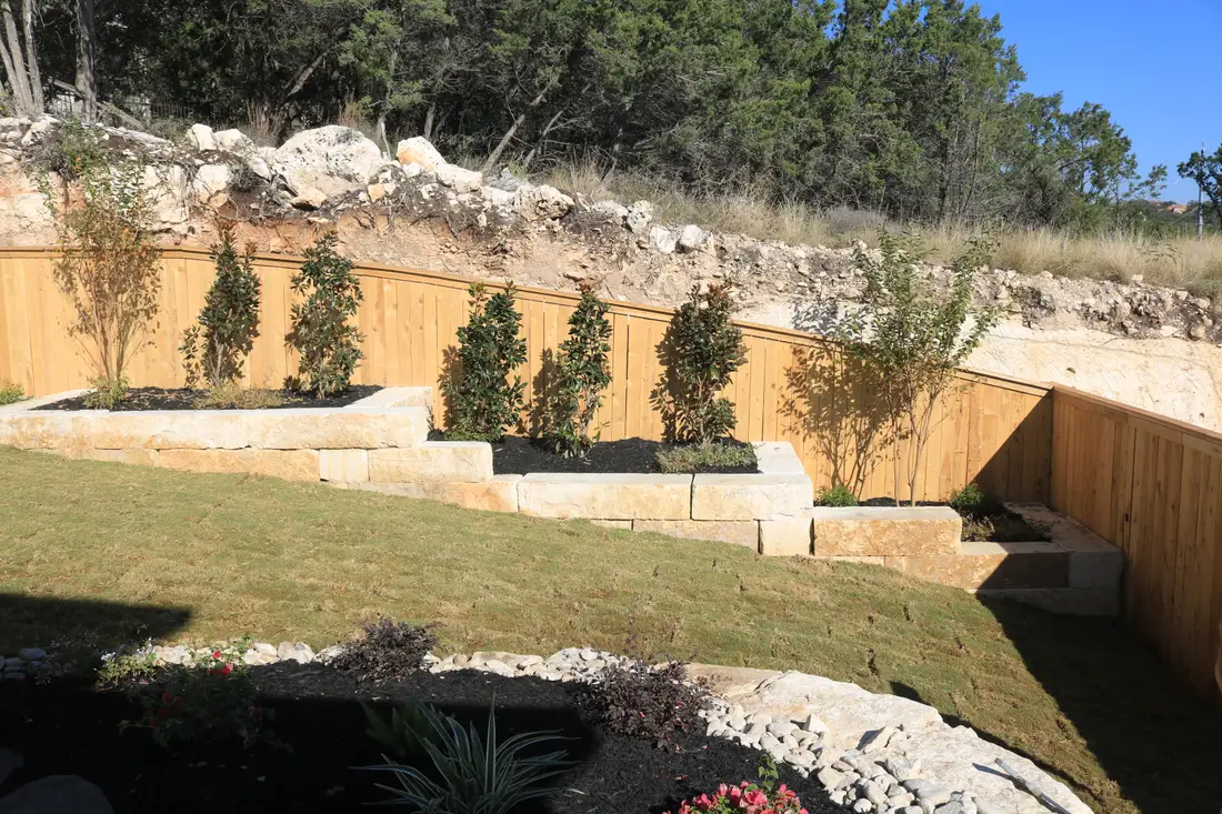 Cut limestone block retaining walls terracing a steep slope, planted between the tiers
