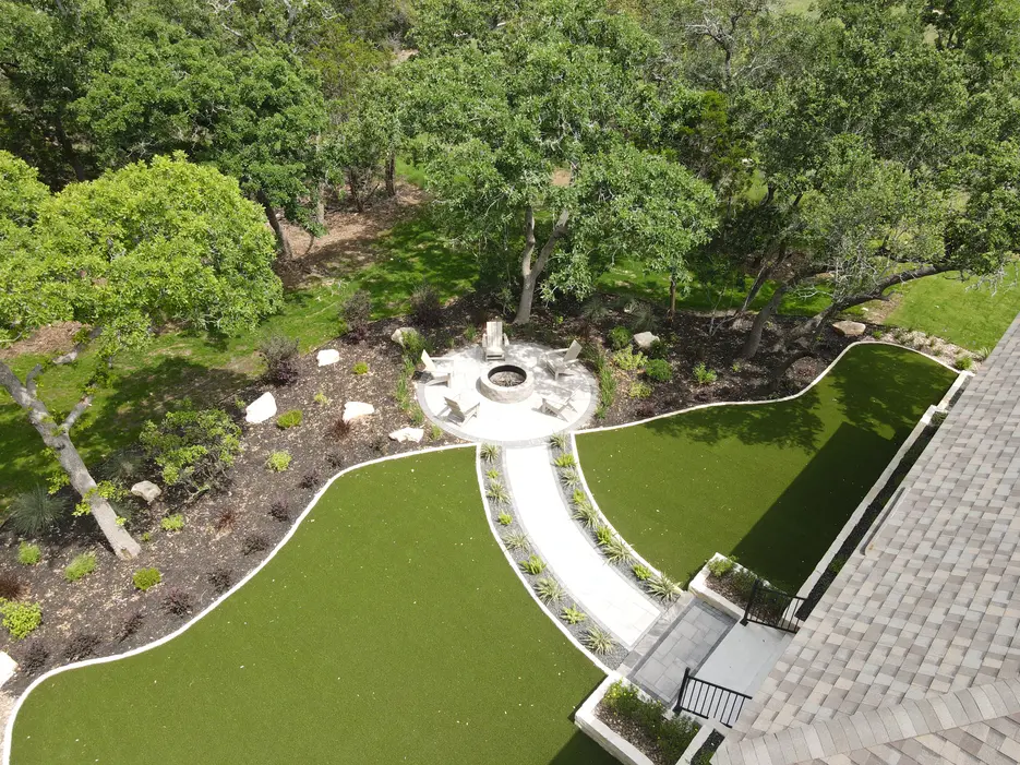 Backyard turf lawn at Thornebrooke with a circular fire pit and limestone seat wall