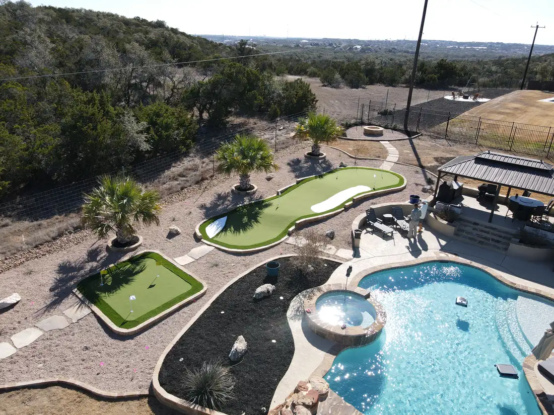 Aerial view of a multi hole putting green built around a pool and palms