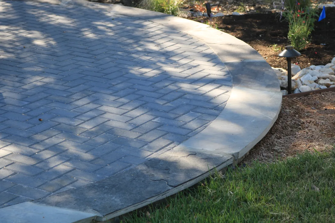 A circular paver patio laid in a fan pattern, set flush into a lawn