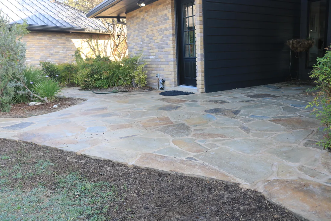 A flagstone patio laid at a side entry, edged into gravel and mulch