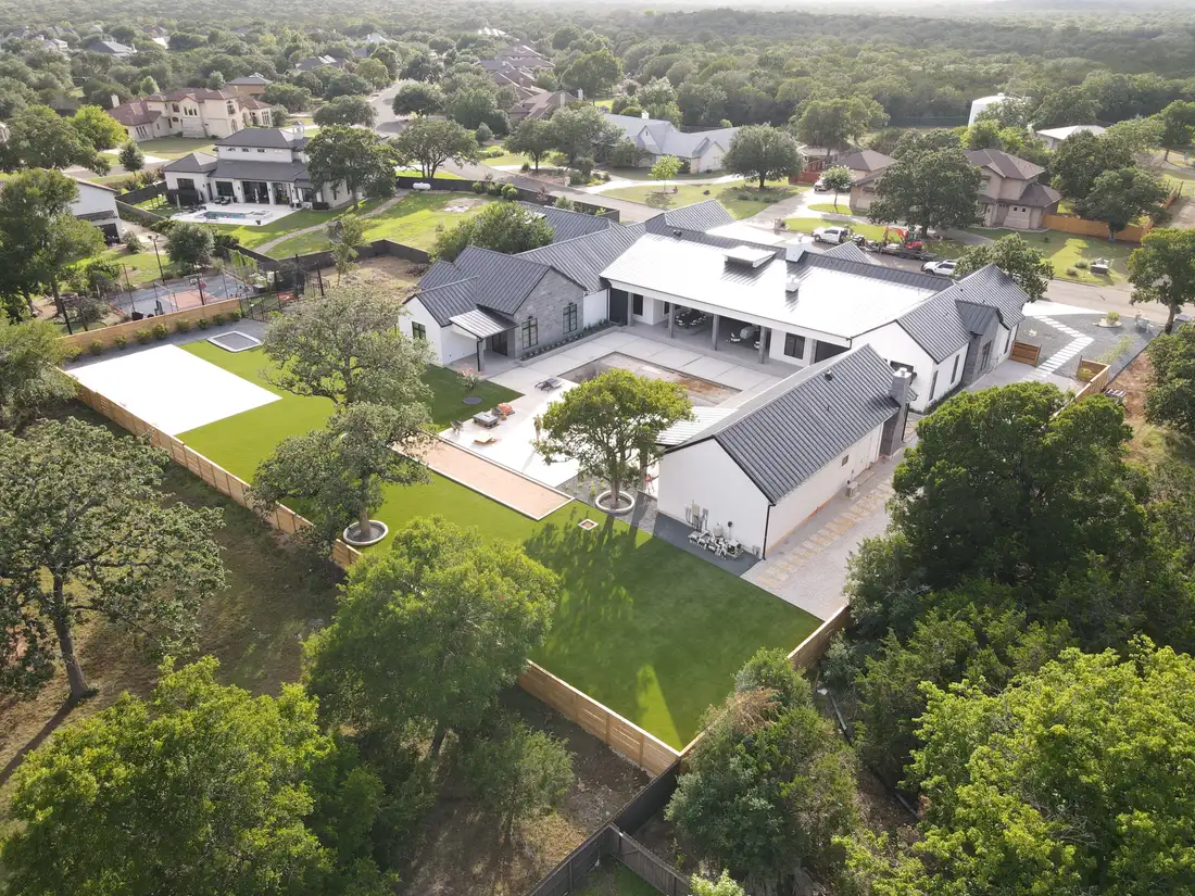 Aerial view of an irrigated Hill Country property with green lawns running up to the house