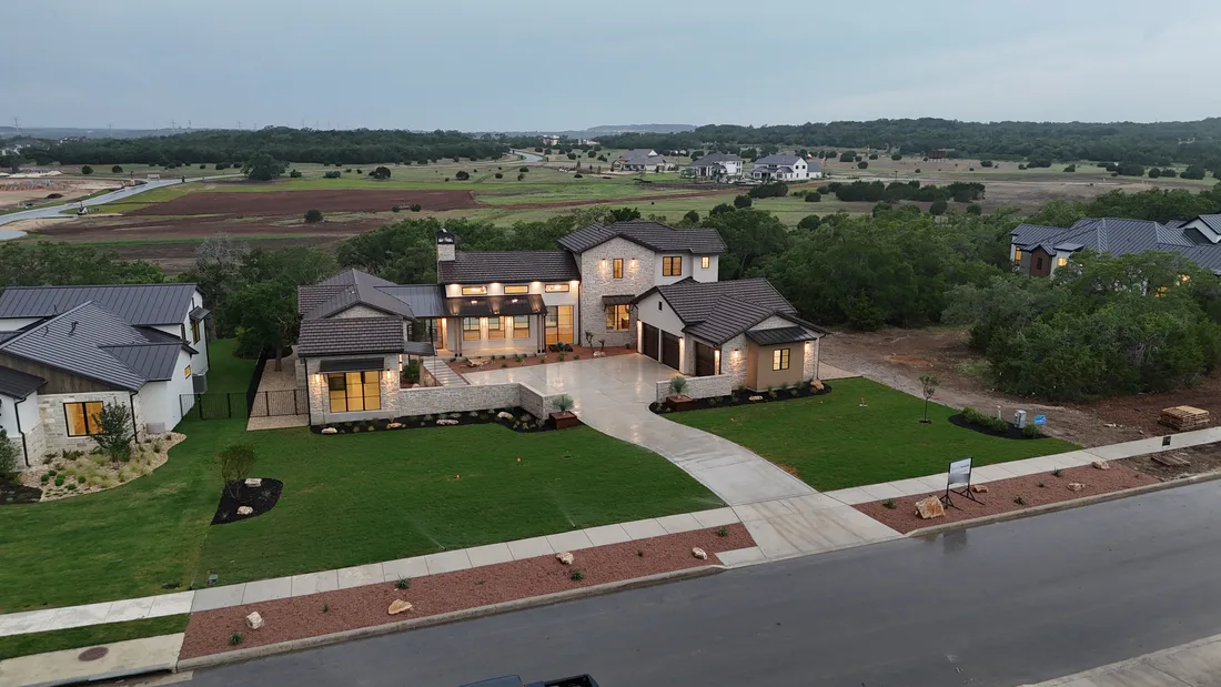 A finished landscape design at dusk, with landscape lighting on a new lawn and planted beds