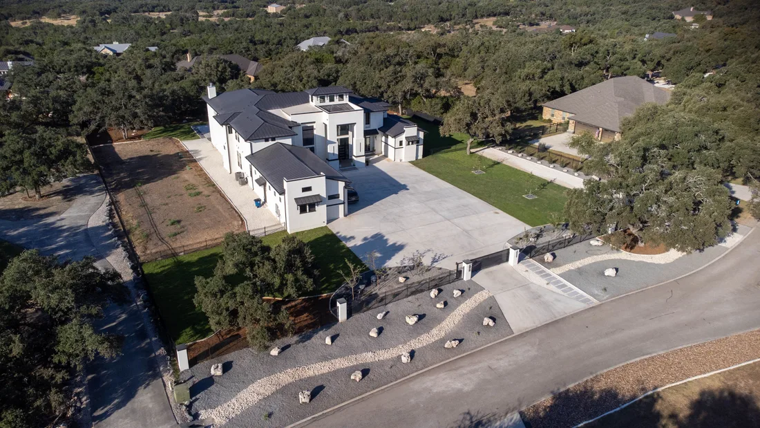 Aerial view of a landscape design on a large lot, with a boulder-lined gravel bed running the length of the drive