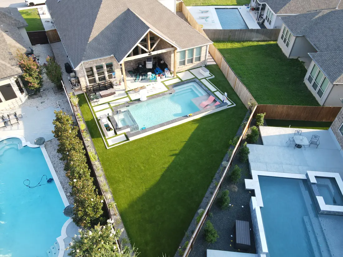 Aerial view of a maintained backyard lawn and pool, mown in clean stripes