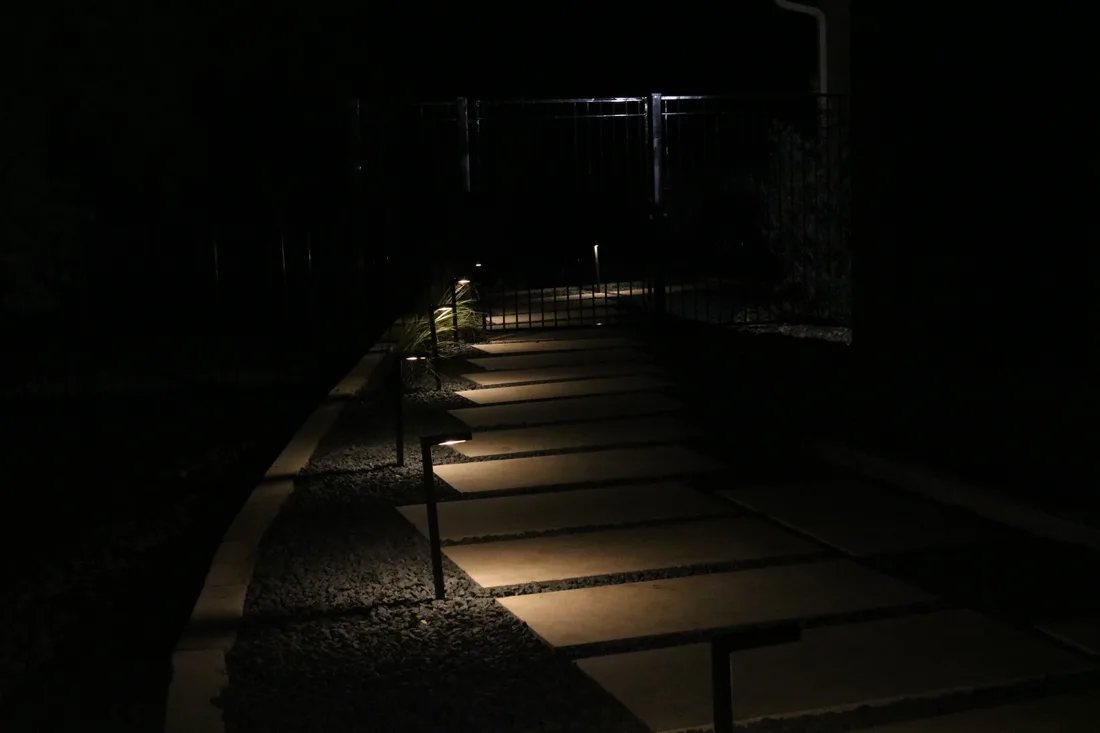 A lit stepper path curving away from the house into the dark