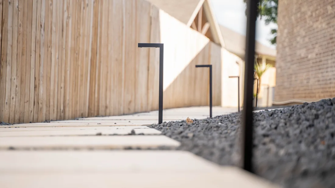 Two low path lights in gravel, throwing light across a stepper and a timber wall
