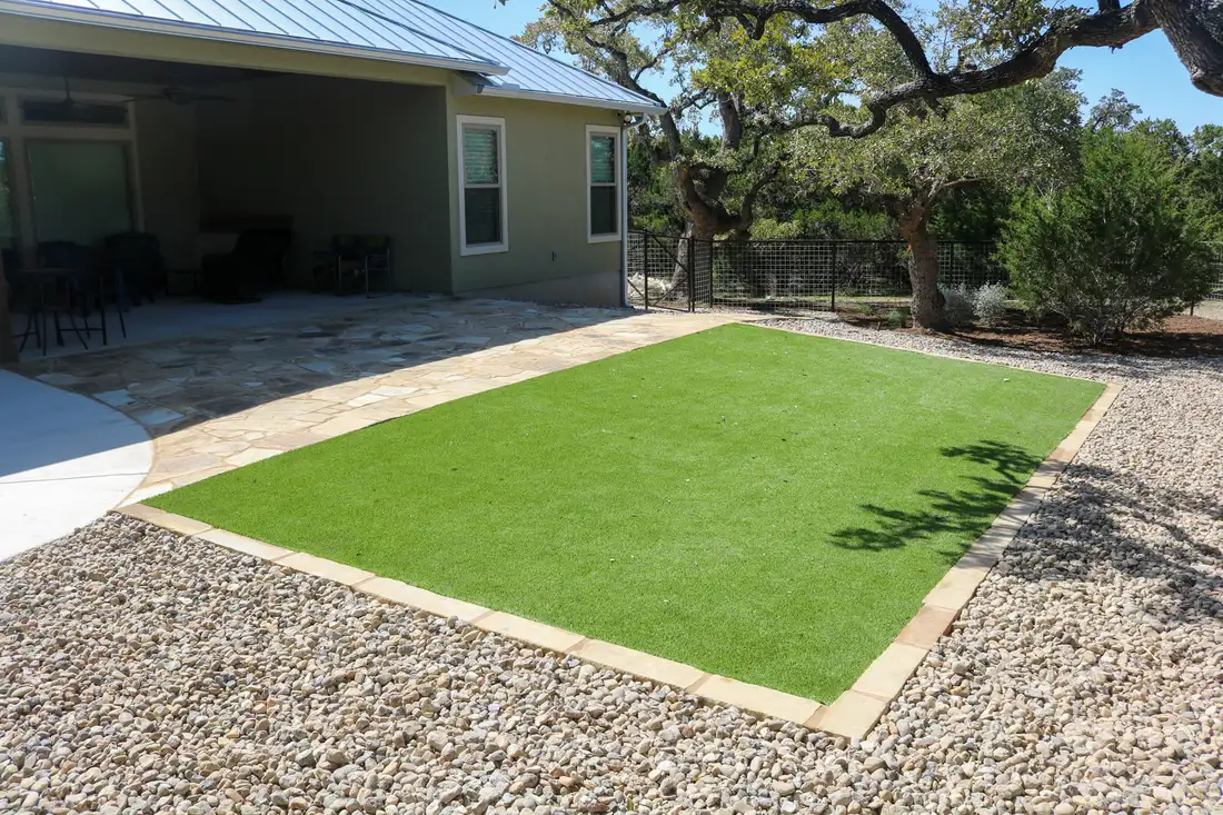 A rectangle of artificial turf edged in stone and set into a gravel surround