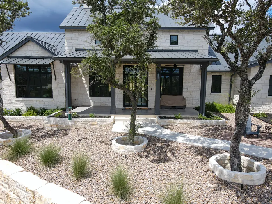 A xeriscaped front yard of gravel and native grasses with limestone tree rings