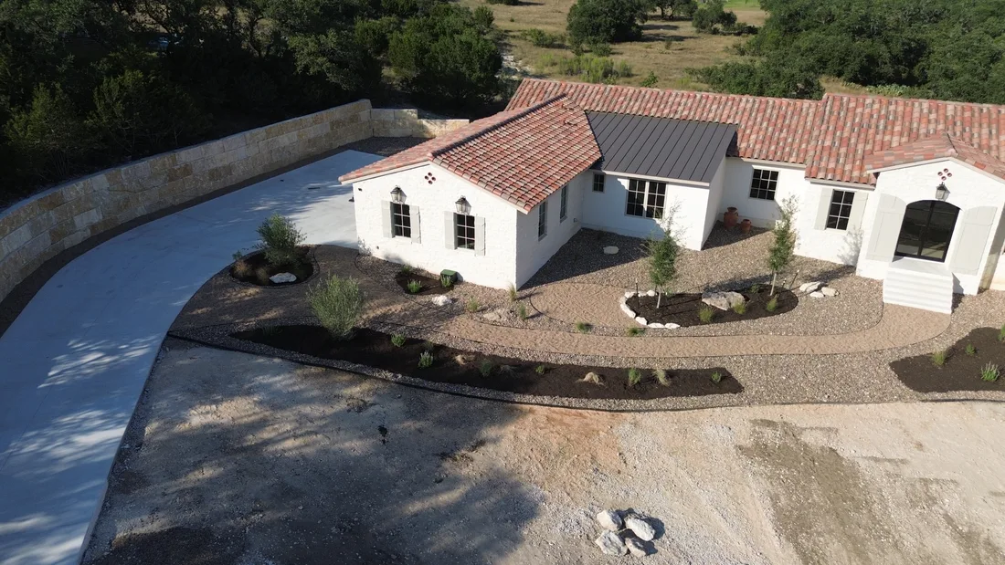 Aerial view of a tile roofed home with gravel beds and stone edging in place of lawn