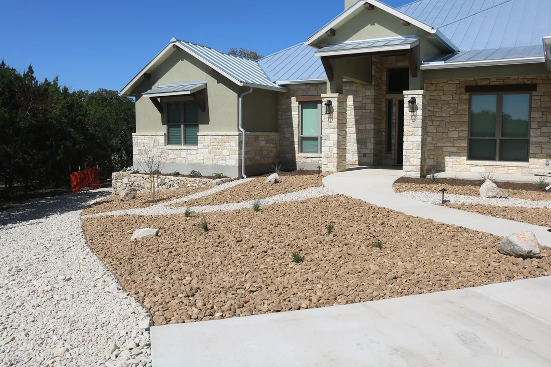 A gravel front yard planted with young natives and edged in cut limestone