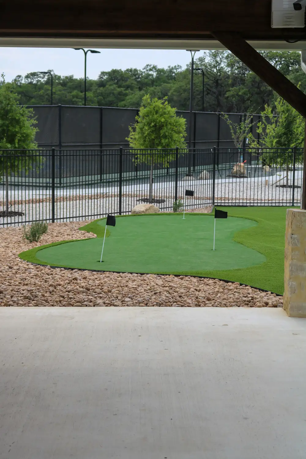 Artificial putting green with a flag, edged in dark mulch and river rock