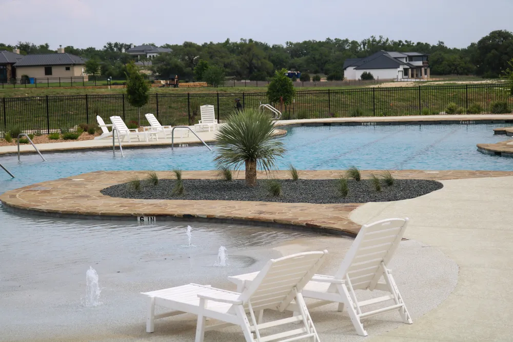 Loungers on the Belle Oaks pool deck with a young palm and planted beds