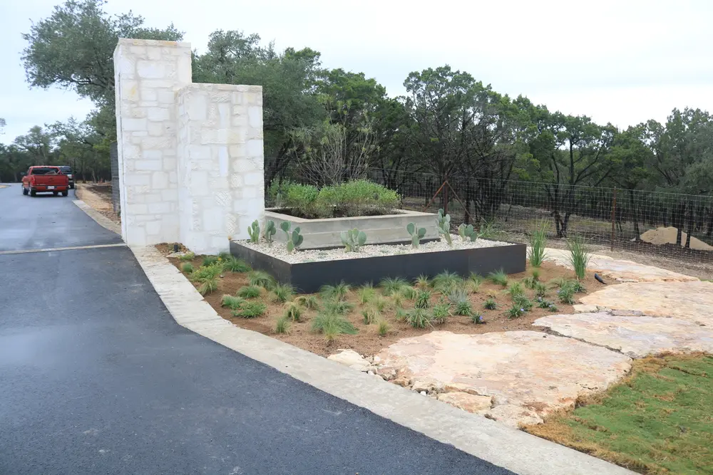 Cut limestone entry monument with a raised planter of native grasses