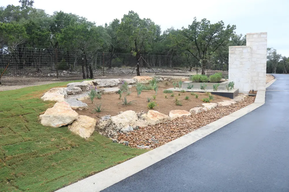 River rock bed with limestone boulders beside a new asphalt drive