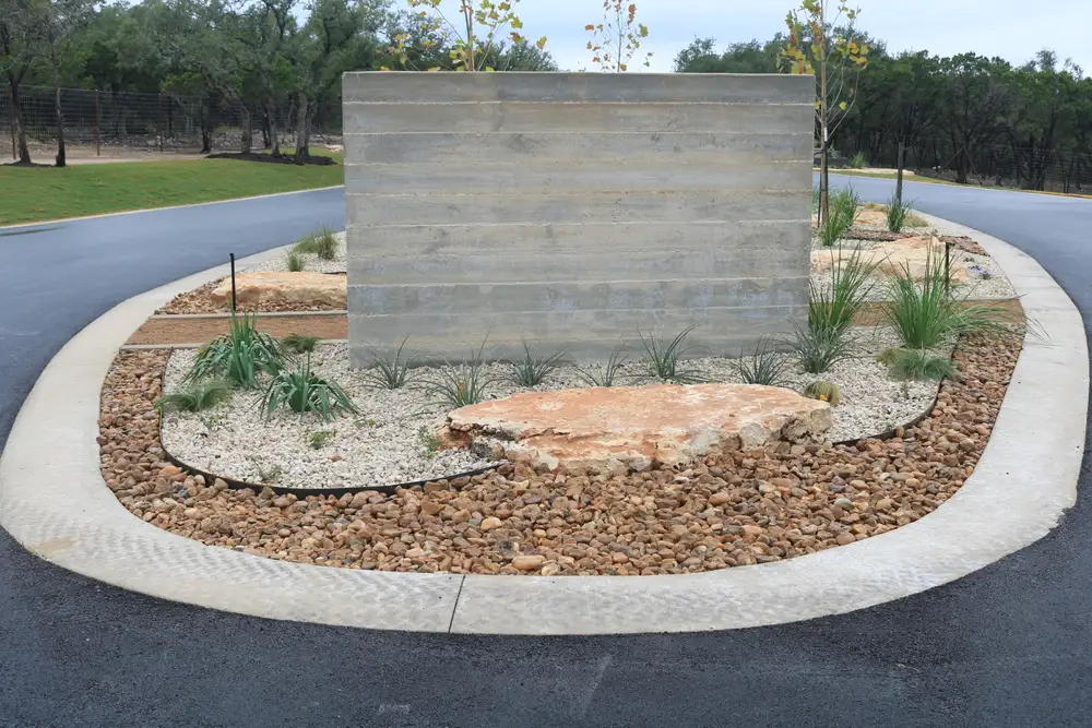 Board-formed concrete wall with limestone boulders and gravel planting