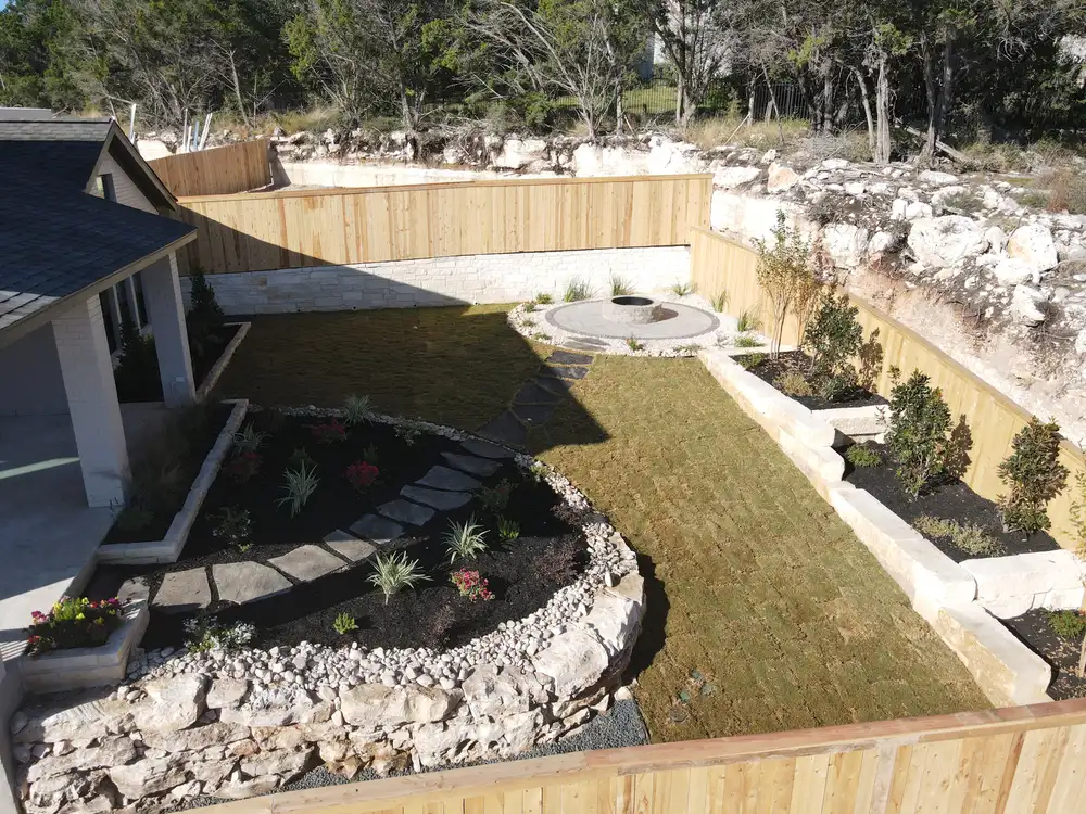 Aerial view of a terraced hillside backyard with flagstone paths and cut limestone walls