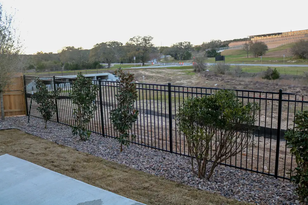Ornamental shrubs in gravel along a black metal fence at the Johnson Ranch model home
