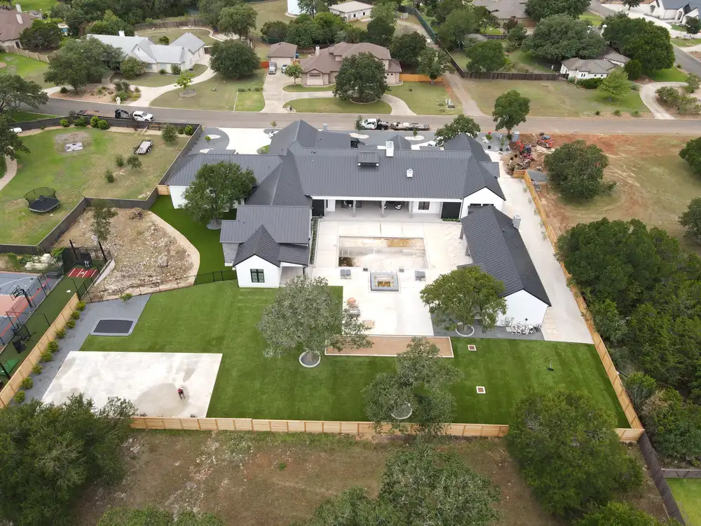 Aerial view of an acreage property with a wide lawn running out to mature oaks