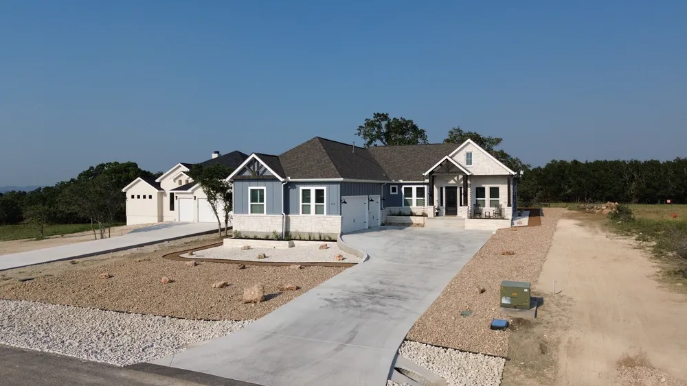 A home with a new concrete driveway and freshly graded beds waiting on planting
