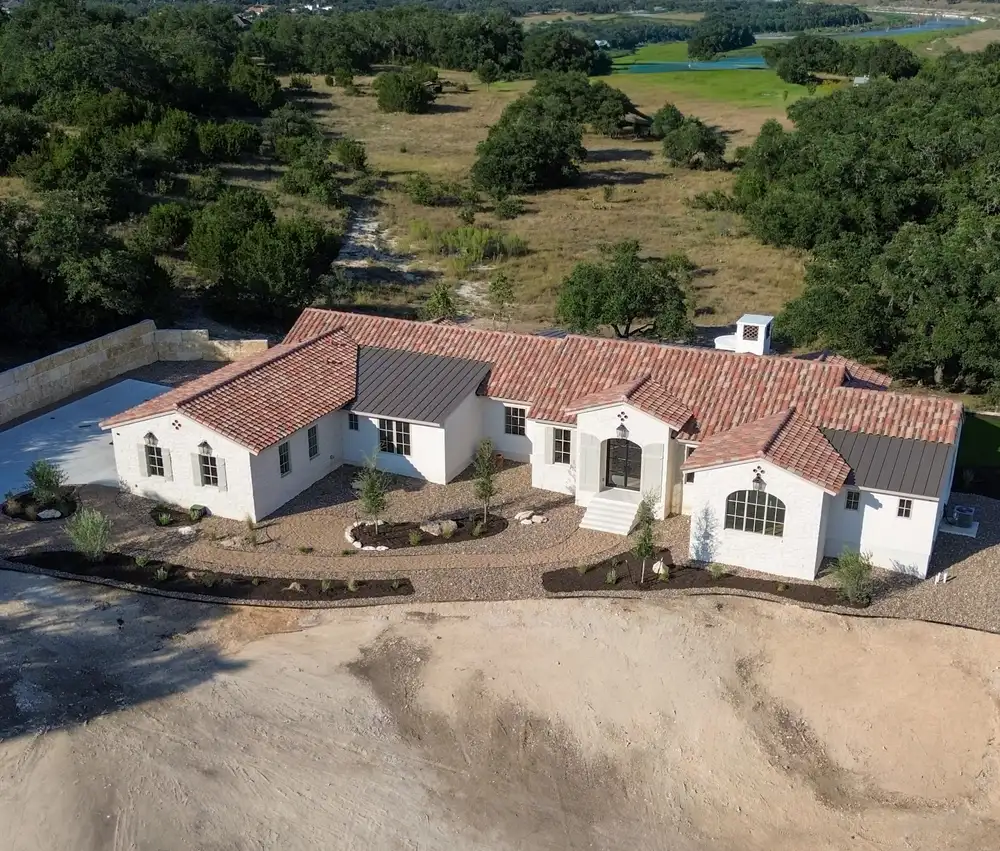 Aerial view of a tile roofed home with gravel planting beds and a newly cleared yard