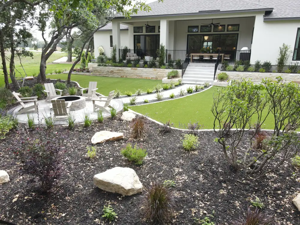 Terraced backyard with turf, limestone boulders, and steps down to a lower lawn
